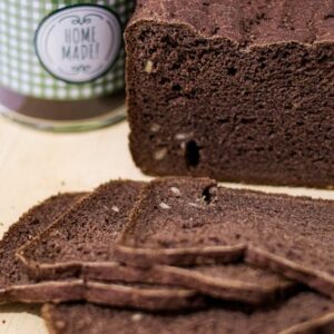 Close-up of homemade chocolate bread with slices and a jar in a kitchen setting.